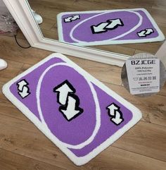 two purple and white rugs sitting on top of a wooden floor next to a mirror