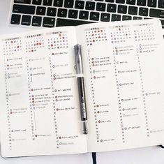 a notebook with a pen on top of it next to a keyboard