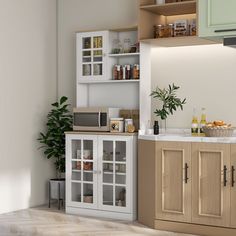 a kitchen with white cabinets and wooden flooring next to a plant in the corner