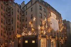 a large building with christmas lights on it's sides and stars hanging from the side