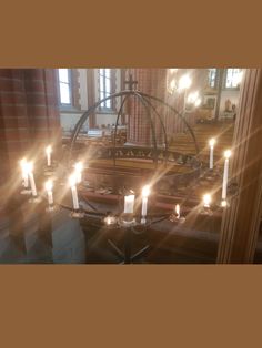 candles are lit in the middle of a room with a chandelier and windows