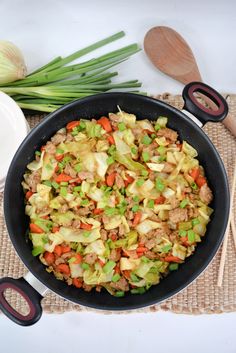 a skillet filled with meat and vegetables on top of a mat