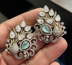 Sabyasachi-inspired Uncut Polki earrings. Adorned with shimmering Moissanite Polki diamonds, they exude timeless sophistication and grace. The intricate Kundan detailing adds a touch of traditional charm, while the peacock-inspired design brings a hint of regal allure. Embrace the richness of Indian heritage and craftsmanship with these exquisite earrings, showcasing the beauty of Uncut Diamonds in a mesmerizing fusion of tradition and contemporary style. *𝐏𝐑𝐎𝐃𝐔𝐂𝐓 𝐃𝐄𝐓𝐀𝐈𝐋* * Material: Brass * Plating: Gold Plated * Stone: Semi Precious Kundan & Polki. *𝐒𝐇𝐈𝐏𝐏𝐈𝐍𝐆 𝐏𝐎𝐋𝐈𝐂𝐘* * Shipping: worldwide from India. * Free shipping: All our products have a free standard shipping policy. So, choosing to shop with us is always free! * The average standard shipping time to the US Elegant Festive Jhumkas With Peacock Design, Elegant Peacock Earrings For Wedding, Elegant Peacock Colored Earrings For Wedding, Elegant Peacock Design Jhumkas For Party, Elegant Peacock Design Bridal Earrings For Festive Occasion, Party Jhumkas With Peacock Design, Elegant Jhumkas With Peacock Design For Celebrations, Elegant Peacock Design Jhumkas For Celebration, Elegant Multicolor Peacock Design Jhumkas