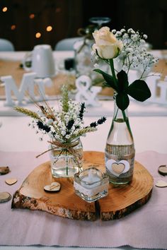 two vases filled with flowers sitting on top of a wooden slab next to each other