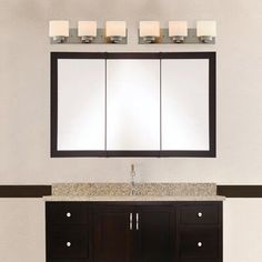 a bathroom vanity with three mirrors above it and lights on the wall behind it in front of a mirror