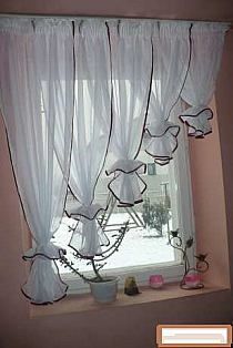 a window with white curtains and flowers on it