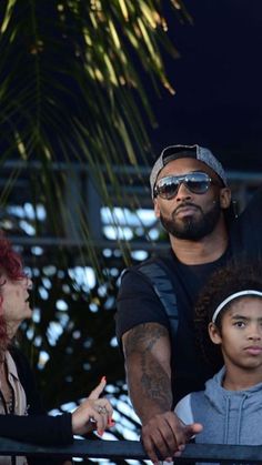 a man and two children standing next to each other in front of a palm tree