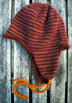 a knitted hat sitting on top of a wooden bench next to an orange string