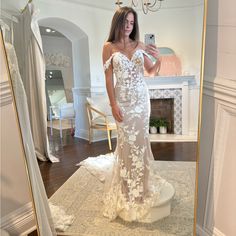 a woman taking a selfie in front of a mirror wearing a white wedding dress