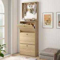 a wooden cabinet with two drawers and pictures on the wall above it in a living room