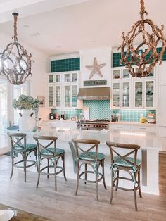 a kitchen with white cabinets and blue accents on the counter tops, island in front of two chandeliers