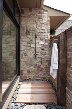 a bathroom with stone walls and wooden flooring next to a walk - in shower