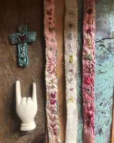 three pieces of fabric are next to a plastic hand and a ceramic object on a wooden surface