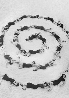 a group of women laying in the sand on their stomachs and legs, all wearing red dresses