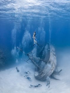 a person is swimming in the water next to a boat that has been washed ashore