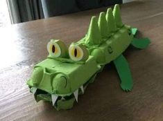 an origami crocodile made out of paper sitting on a table with its mouth open