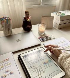 a person sitting at a desk with an ipad and notebook in front of them,