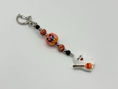 a keychain with a white cat on it's side and beads hanging from the end