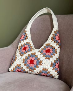 a crocheted purse sitting on top of a couch next to a brown chair