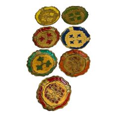 five different colored glass plates sitting on top of a white surface with gold and red designs