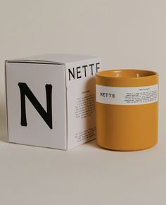 a yellow coffee mug sitting next to a white box with the letter n on it