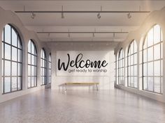 an empty room with large windows and a welcome sign on the wall