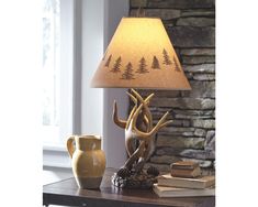 a lamp that is sitting on top of a table next to a vase and book