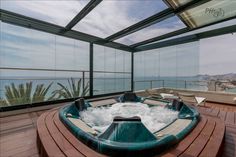 a large hot tub sitting on top of a wooden floor next to a balcony overlooking the ocean