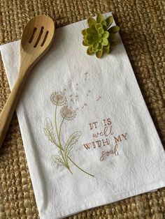 a napkin with a flower on it and a wooden spoon sitting next to it that says it is well with my soul