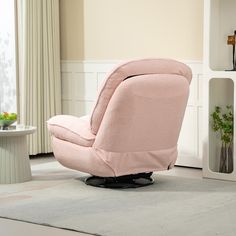 a pink recliner chair sitting on top of a rug in front of a window