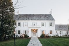 a large white house sitting on top of a lush green field