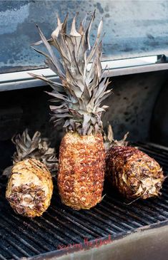 three pineapples sitting on top of an open grill