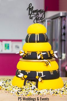 a yellow and black wedding cake on top of a table with confetti around it