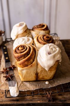 cinnamon rolls with icing and star anise on a wooden board next to a knife