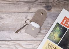 a book with a keychain on top of it next to a cell phone