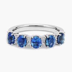 a ring with blue stones and diamonds on the sides, set in 18k white gold