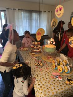 a group of people standing around a table with cupcakes