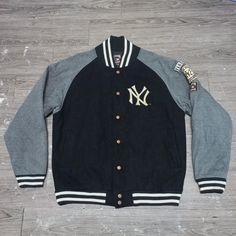 a black and grey jacket with the new york yankees on it sitting on a wooden floor