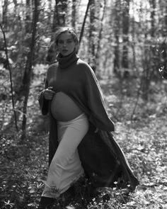 a pregnant woman is standing in the woods