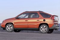 an orange car is parked on the side of the road with mountains in the background