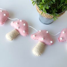 some pink and white mushrooms are hanging on a string next to a potted plant