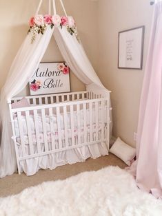 a baby's room with a white crib and pink flowers hanging from the ceiling