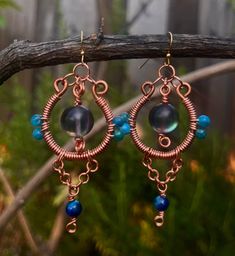 a pair of earrings with blue beads hanging from it's hooks on a tree branch