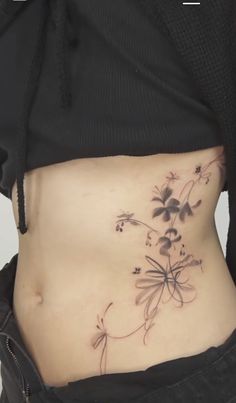 a woman's stomach with flowers and leaves tattooed on the side by her belly