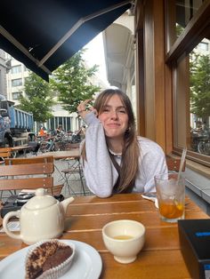 a woman sitting at a table with food and drinks