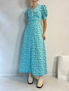 "- Vintage handmade blue floral peasant dress - Zipper and ties at the back - Feels like a thick polyester - No tags - Small  Bust: 19\" Waist: 15.5\" Length: 53\"" Blue Ditsy Floral Print Maxi Dress For Garden Party, Blue Ditsy Floral Print Short Sleeve Maxi Dress, Green Floral Print Puff Sleeve Maxi Dress, Green Puff Sleeve Maxi Dress With Floral Print, Blue Puff Sleeve Maxi Dress For Summer, Casual Blue Maxi Dress With Ditsy Floral Print, Light Blue Floral Print Maxi Dress For Daywear, Casual Blue Puff Sleeve Maxi Dress, Light Blue Floral Maxi Dress For Daywear