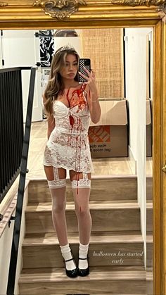 a woman taking a selfie in front of a mirror with blood on her body