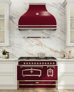 a red stove top oven sitting inside of a kitchen next to white cabinets and counter tops