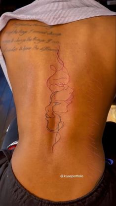 a woman's back with a tattoo on her left side and words written in red ink