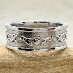 a wedding band with an anchor and heart in the center on top of a rock